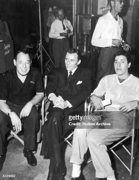 American actor and singer Frank Sinatra sits next to American actors and comedians Joe E. Lewis and Jerry Lewis on the set of director Charles...