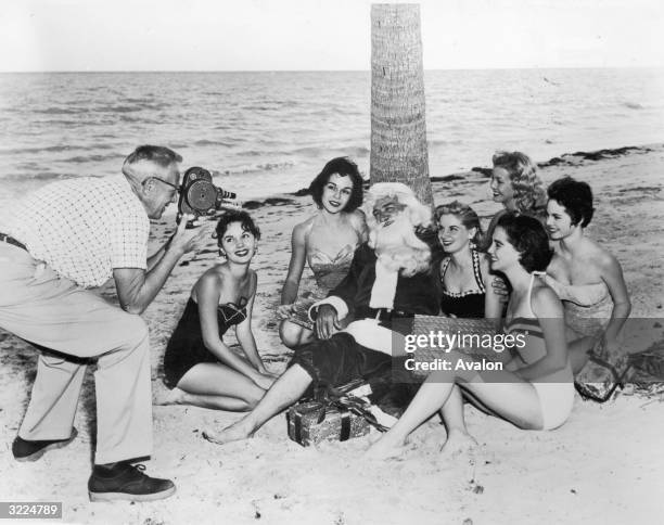 Santa Claus and a group of sunbathers posing for a cameraman on a beach in Miami, Florida.