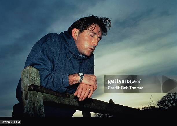 man leaning,exhausted,on gate, sweating heavily,eyes closed - sin aliento fotografías e imágenes de stock