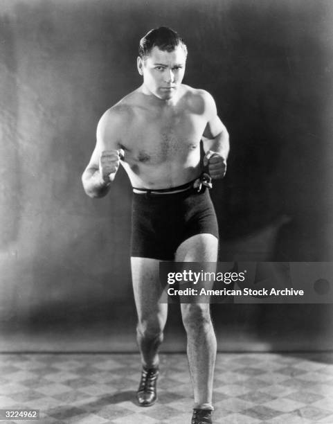 Full-length studio portrait of American heavyweight boxing champion Jack Dempsey clenching his fists in a fighting stance.