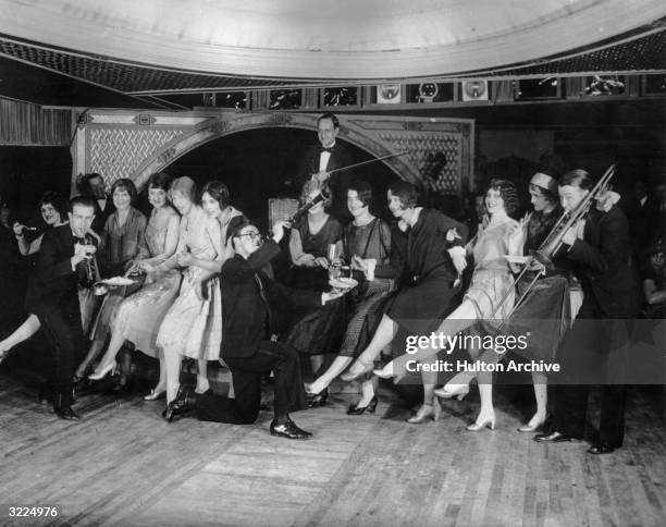 Female flappers kicking, dancing, and having fun while musicians perform during a Charleston dance contest at the Parody Club.