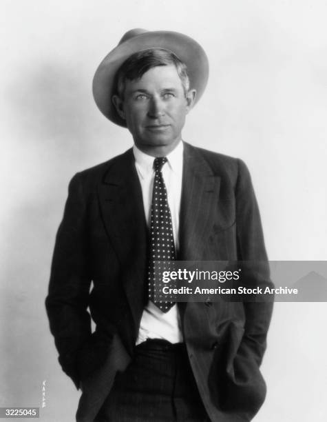 Studio portrait of American actor, humorist, and lecturer Will Rogers wearing a hat and a polka dot tie with a pinstriped suit.