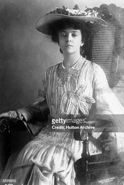 Portrait of Alice Roosevelt , eldest daughter of Theodore Roosevelt, wearing a hat and appliqued dress while sitting in a chair.
