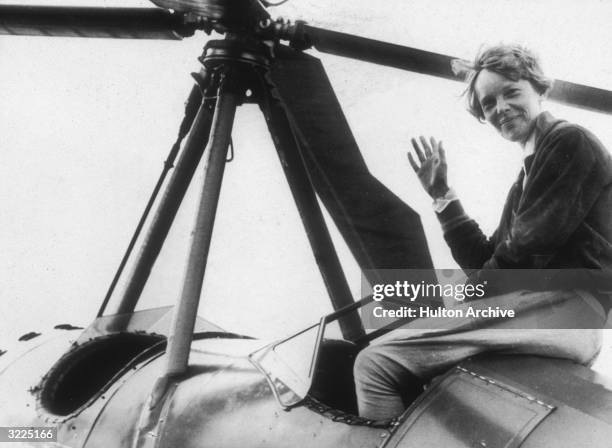 American aviator Amelia Earhart , the first woman to complete a solo transatlantic flight, waves as she emerges from the cockpit of a rotorcraft,...