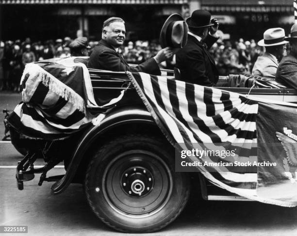 President Herbert Hoover waves his hat in recognition of the crowds surrounding his car in a parade, San Francisco, California.