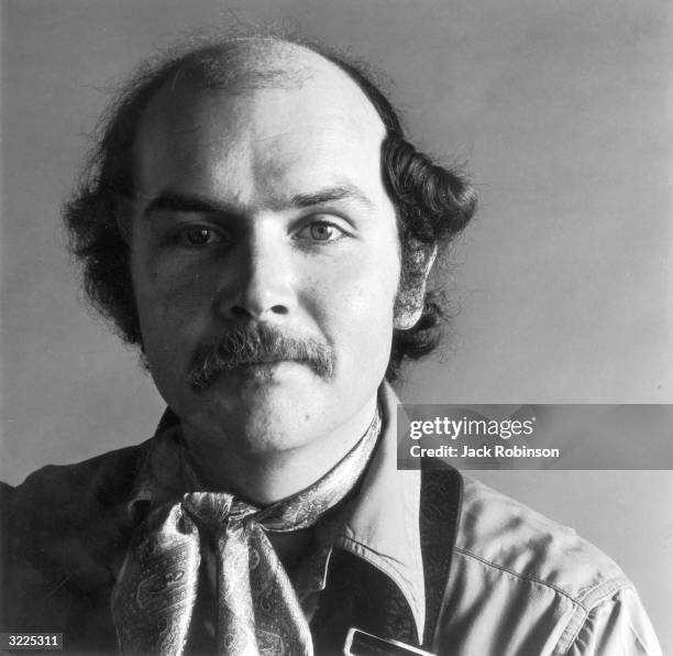 Studio headshot portrait of American folk singer and songwriter Tom Paxton smiling and wearing a paisley scarf.