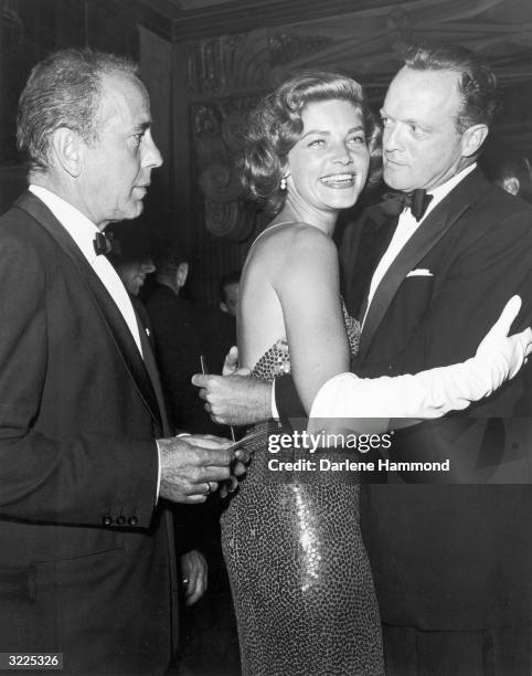 American actors Lauren Bacall and Van Heflin dance at a formal party while Bacall's husband, American actor Humphrey Bogart , looks on, early 1950s....