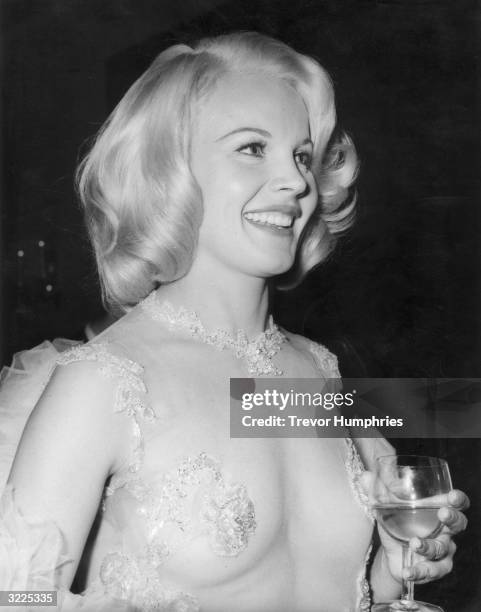 American actress Carroll Baker wearing a transparent dress at Claridges in London following the film premiere of 'The Carpetbaggers.'