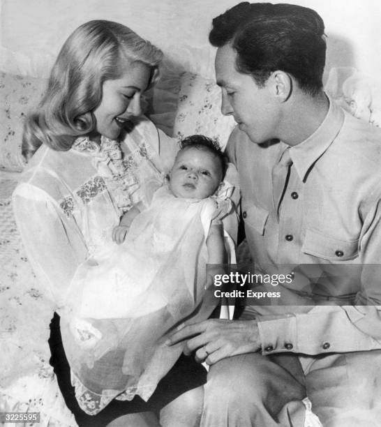 American actor Lana Turner smiles while holding her newborn daughter, Cheryl Crane, next to her second and third husband , Stephen Crane. Crane is...