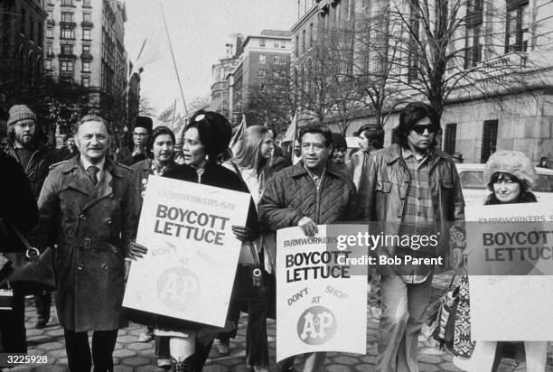 Labor rights leader Cesar Chavez and Coretta Scott King leading a lettuce boycott march down a street in New York City. They are holding placards.
