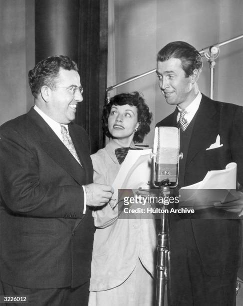 American orchestra leader John Scott Trotter, American singer Kay Starr, and American actor James Stewart smile while holding scripts behind a...