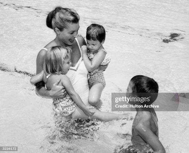 American swimmer and actor who starred in aquatic musicals, Esther Williams, playing with her three children, Susan, Kimball and Ben, in a pool.
