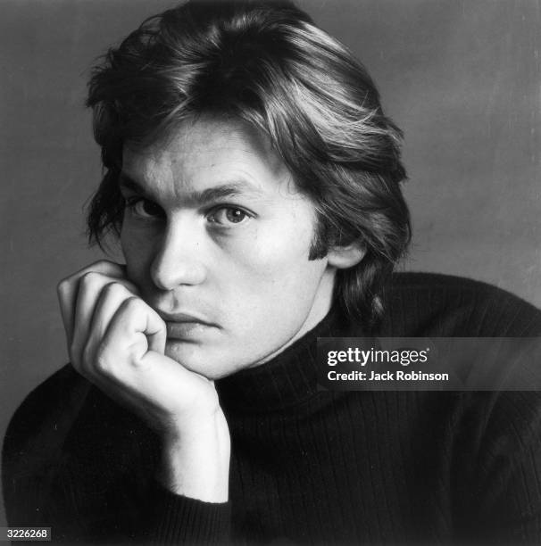 Studio headshot portrait of Austrian actor Helmut Berger, resting his chin on one hand.