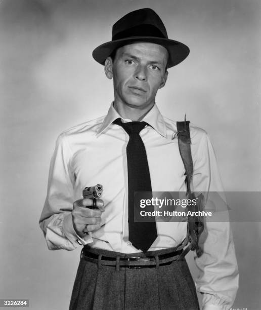 American actor and singer Frank Sinatra wearing a hat, holster and pointing a gun, in a promotional portrait for director Lewis Allen's film,...