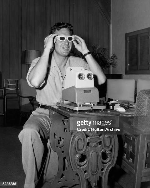 American actor Robert Stack views three dimensional slide pictures with his special projector and 3-D glasses. Stack starred in the first full-length...