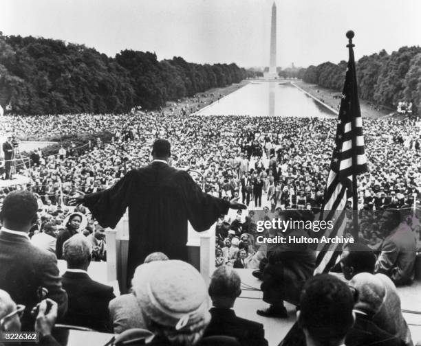 Back view of American civil rights leader and Baptist minister Martin Luther King, Jr. , dressed in black robes and holding out his hands towards the...