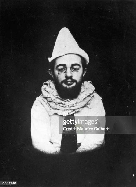 Studio portrait of French painter and graphic artist Henri Toulouse-Lautrec , bearded and wearing a pince-nez, posing as Pierrot the clown with a...