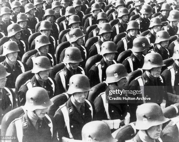 Rows of Nazi SS troops, also known as the Schutzstaffel, stand in uniform at Nuremberg, Germany. They wear helmets with a double lightning bolt...