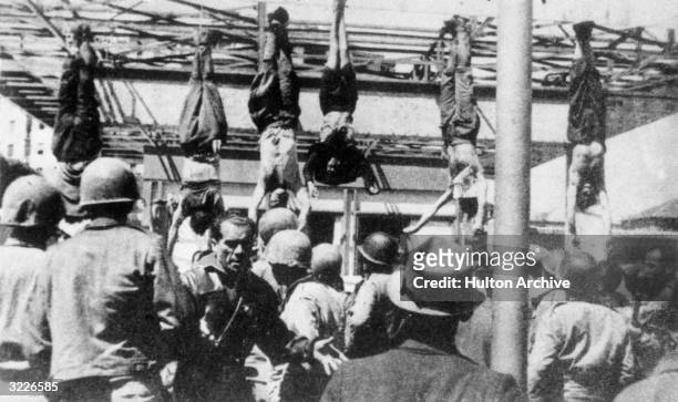 Italian fascist leader Benito Mussolini and others captured with him, including his mistress, Clara Petacci, hang by their feet from a filling...