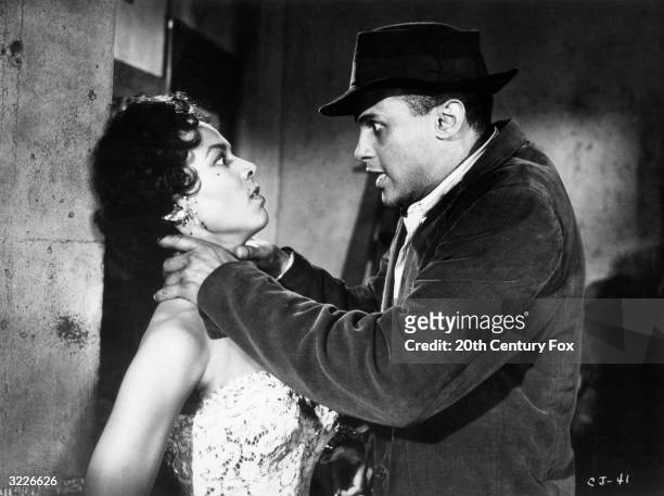 American actor Harry Belafonte holding his hands around the neck of actor Dorothy Dandridge in a still from director Otto Preminger's film, 'Carmen...