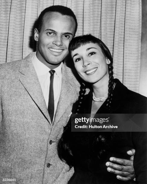 American singer and actor Harry Belafonte smiling with his arm around the waist of his second wife, American dancer Julie Robinson. Robinson wears...