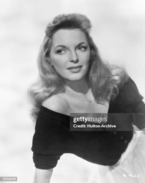 Studio portrait of American actor and singer Julie London wearing a V-neck sweater and a skirt.