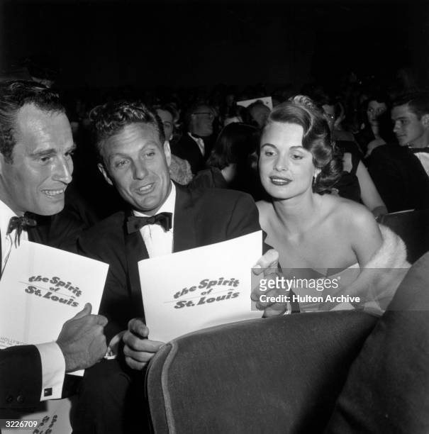American actors Charlton Heston and Robert Stack look at their programs while sitting in a theater with Stack's wife, Rosemarie Bowe, at the premiere...