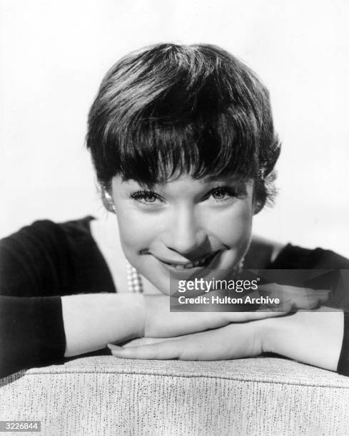 Promotional headshot portrait of American actor Shirley MacLaine smiling with her chin resting on her hands, for director Billy Wilder's film, 'The...