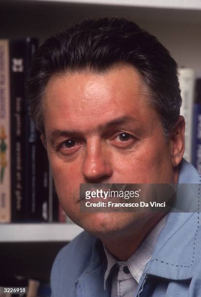 American film director Jonathan Demme posing in front of a bookcase.