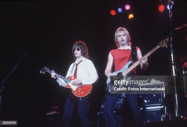 American rock guitarist Elliot Easton and bassist Benjamin Orr performing on stage with the group the Cars. Easton wears sunglasses, a white shirt,...