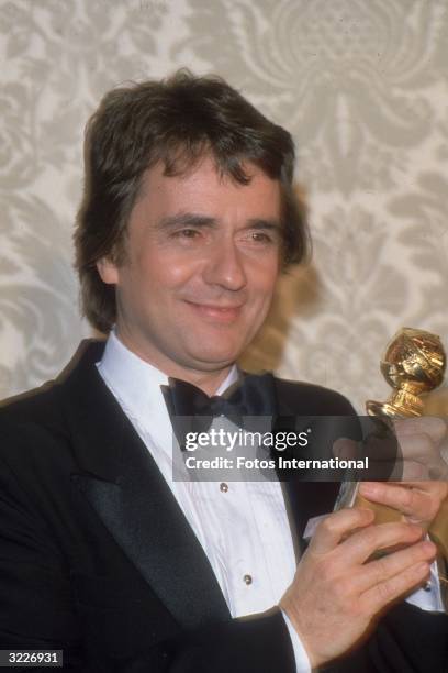 Headshot of British actor Dudley Moore smiling while holding the Best Motion Picture Actor - Comedy/Musical statuette he won for director Steve...