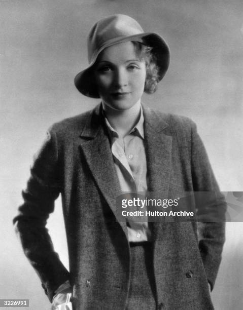 German-born actor Marlene Dietrich , wearing a blazer and a hat, with her hands by her hips, circa 1925.