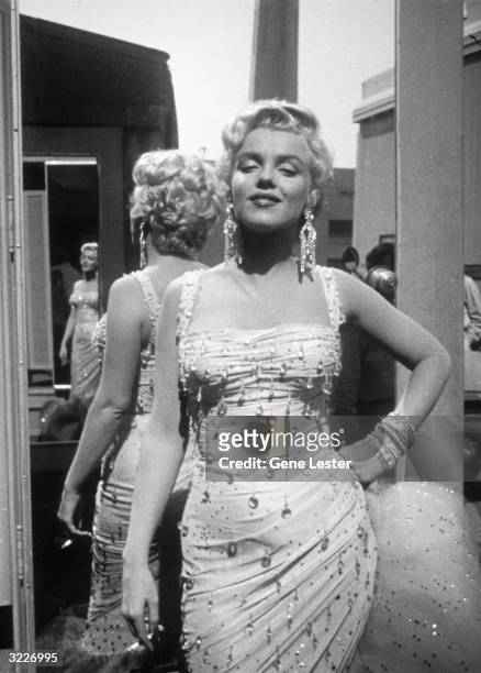 Portrait of American actor Marilyn Monroe posing in a white beaded gown, on the 20th Century Fox studios set of director Walter Lang's film, 'There's...