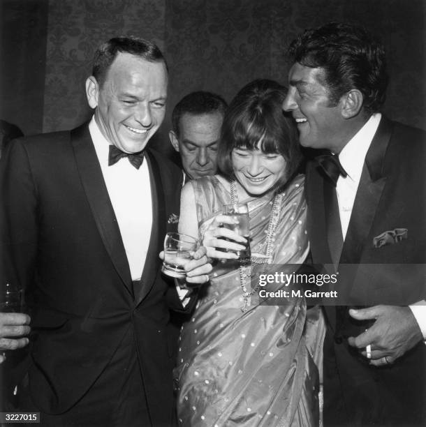 Left to right, American singer and actor Frank Sinatra, wearing a tuxedo, American actor Shirley MacLaine, wearing a sari, and American singer and...