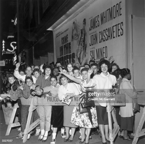 Fans of American actor Sal Mineo waving from behind a police barricade at the premiere of the Don Siegel film 'Crime in the Streets' at the Victoria...