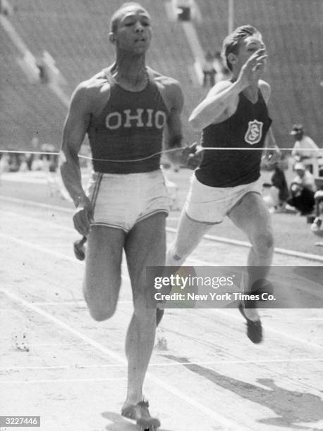 Full-length image of American track and field athlete Jesse Owens breaking the ribbon while crossing the finish line, winning the 100-yard dash for...