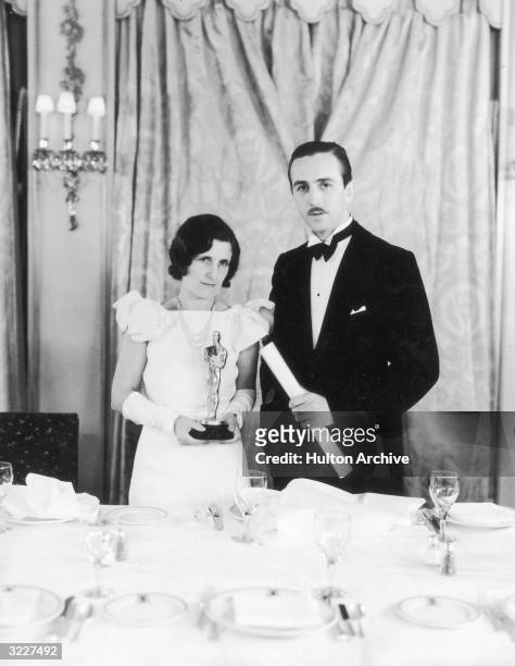 American animator and producer Walt Disney stands next to his wife, Lillian Bounds, who is holding one of Disney's Oscars, possibly at an Academy...