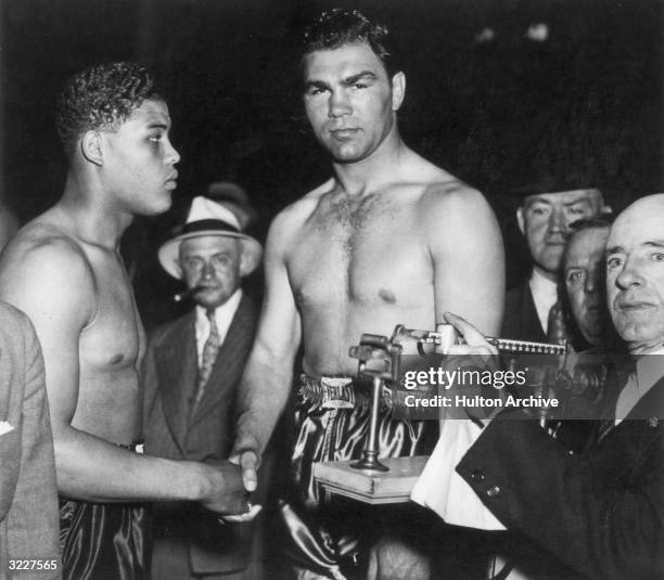 German boxer Max Schmeling shakes hands with American boxer Joe Louis while being weighed in before one of their fights.