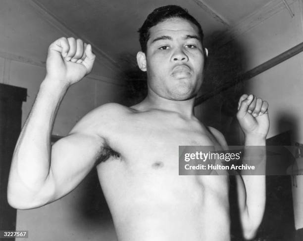 Low-angle view of American heavyweight boxer Joe Louis holding his fists at shoulder level.