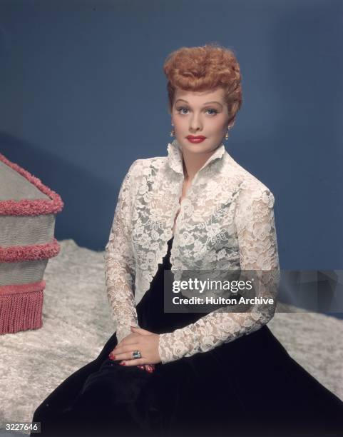 Studio portrait of American actor and comedian Lucille Ball wearing a white lace bolero jacket over a black gown.