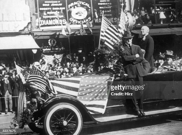 President Woodrow Wilson stands in a car and is cheered by enthusiastic crowds as he passes through the streets of San Francisco, California.