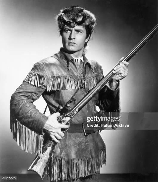 Promotional studio portrait of American actor George Montgomery , wearing a pioneer costume and holding a rifle, for director Phil Karlson's film...