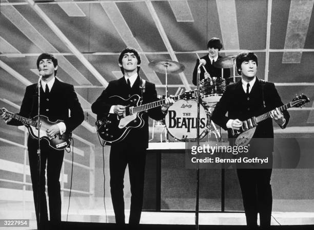 View of the members of British Rock group the Beatles as they perform onstage during their debut appearance on 'The Ed Sullivan Show' at CBS's Studio...