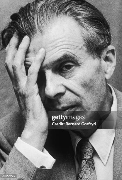 Headshot portrait of British writer Aldous Huxley holding his hand to his face, New York City.