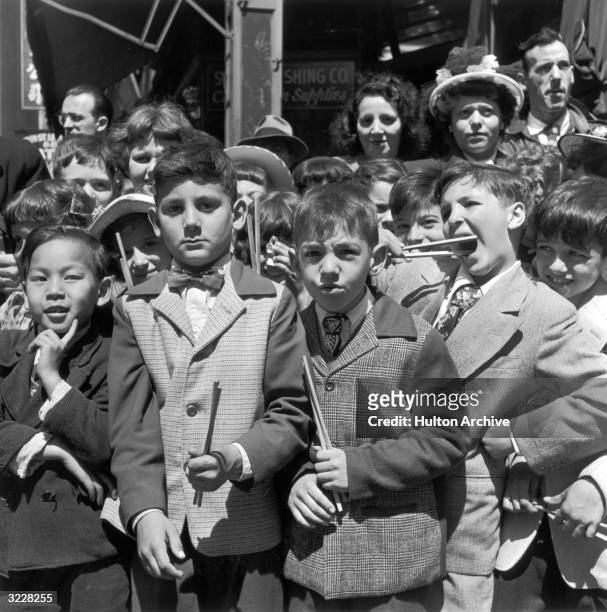 Group of boys stand on the sidewalk, holding chopsticks, as they watch the on location production of director Stanley Donen's film, 'On the Town,'...