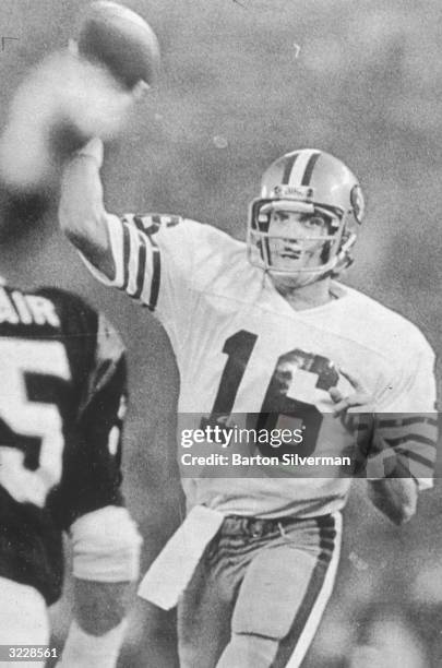 San Francisco 49ers quarterback Joe Montana runs while holding a football in the air after completing a successful pass during Super Bowl XVI. The...