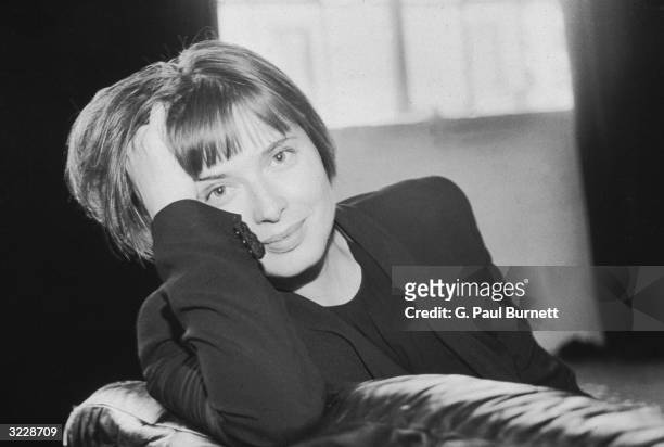 Portrait of Italian actor and model Isabella Rossellini, daughter of Ingrid Bergman and Roberto Rossellini, smiling and resting her head on her...