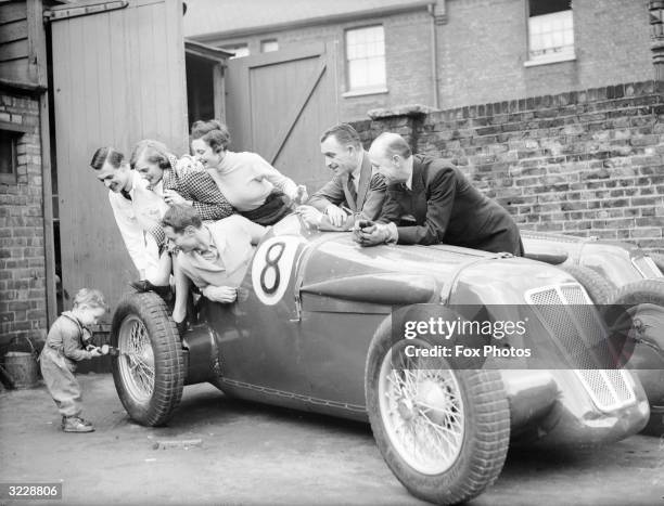 Two year old Bunny Almack making an adjustment to his fathers sports car while he and other members of the British Suicide stunt team Squad watch in...