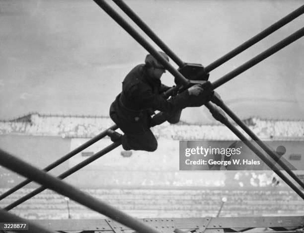 Riveter carrying out repairs to the main girders of the Blackpool Tower in preparation for the coming holiday season.