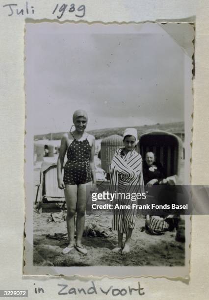 Full-length portrait of Margot and Anne Frank on a beach with their grandmother in the background taken from Anne's photo album, Zandvoort.